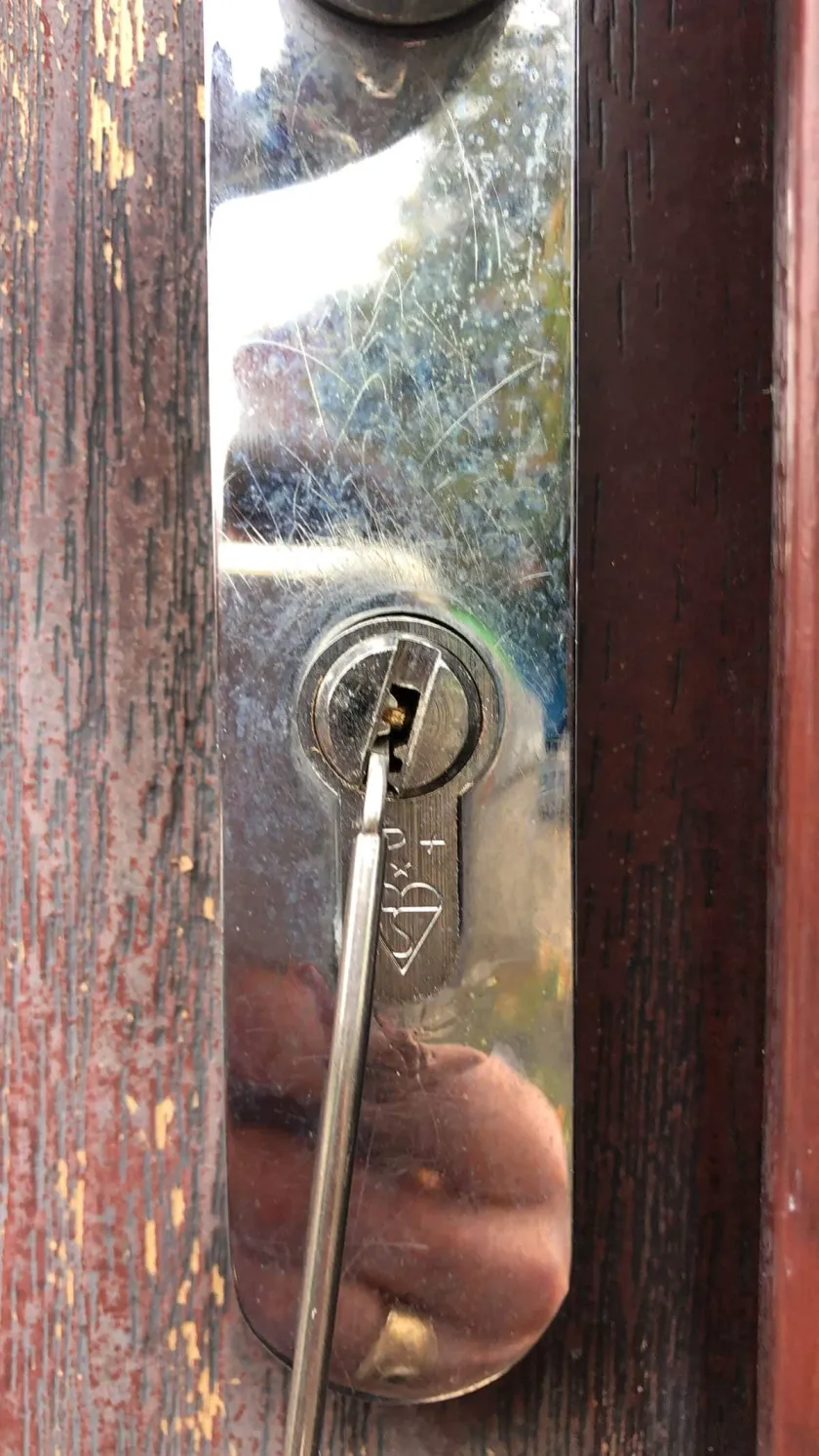 Locksmith picking a three-star anti-snap euro cylinder on a timber front door