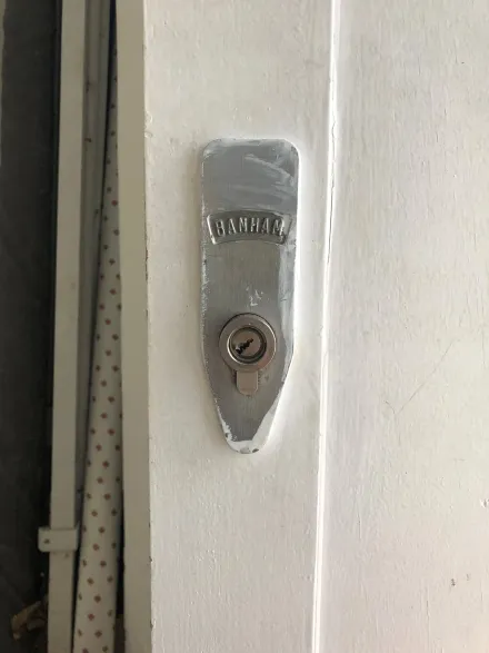 Banham rim lock plate on a white door after non-destructive entry