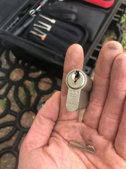 Three-star ABUS cylinder and the recovered snapped key blade held over the pick case