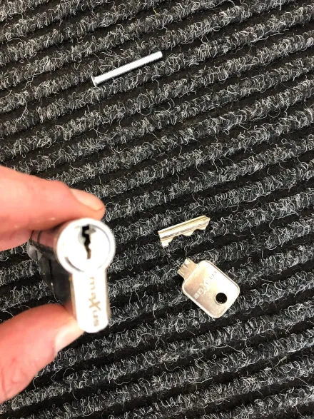 Euro cylinder in hand with the snapped key extracted onto the doormat