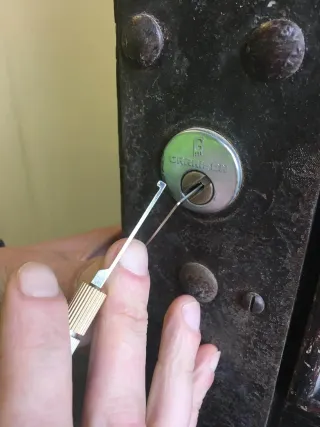 Garrison rim cylinder picked open on a rusted stud-plated door, tension tools in hand