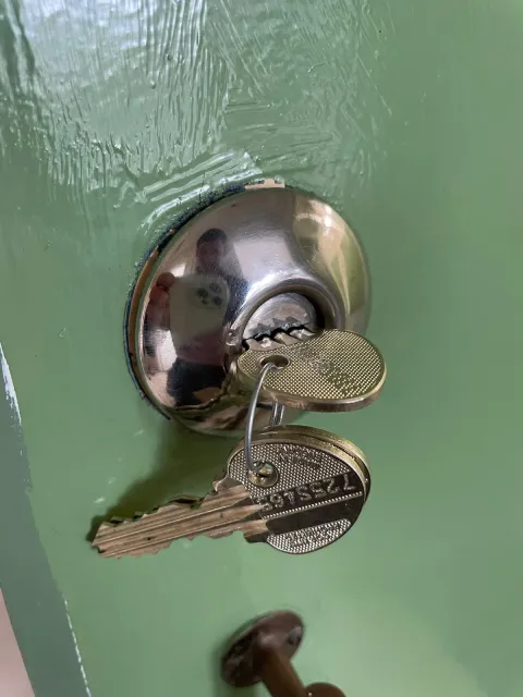 New chrome rim cylinder with two fresh keys on a green front door after a rekey in Ruislip
