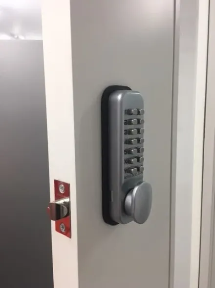 Push-button code lock fitted to a white office door