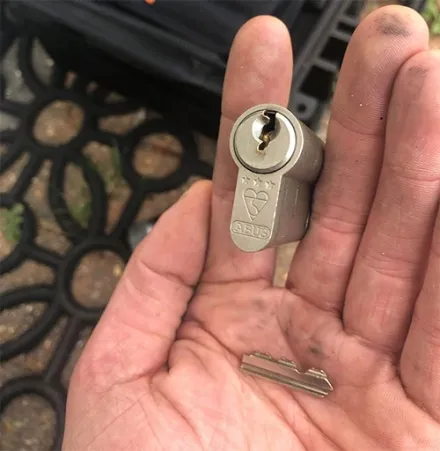 ABUS euro cylinder and a snapped key held in an open palm