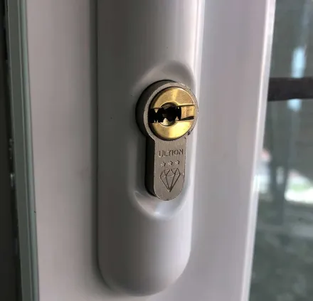 Close-up of an Ultion three-star cylinder in a white uPVC handle plate