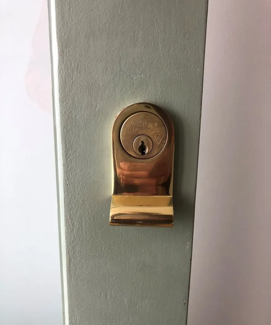 Polished brass Yale rim cylinder fitted to a sage-green front door: everyday lock work priced upfront